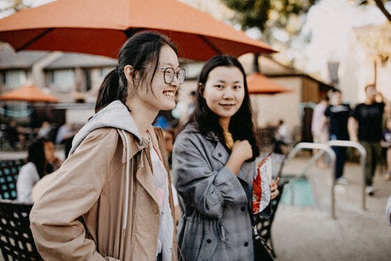 two women standing next to each other on a street