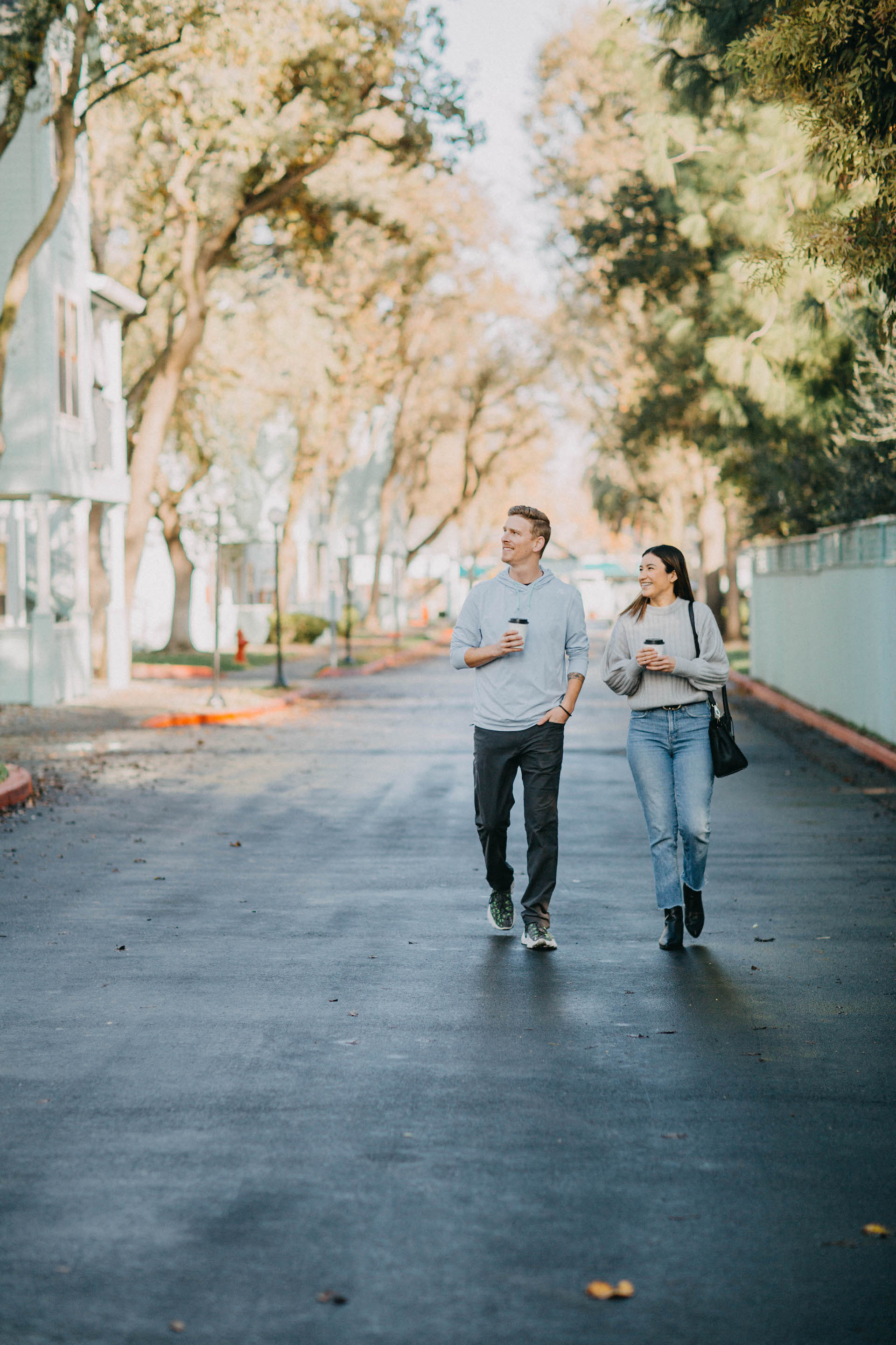 A young man and young woman walking together holding coffee