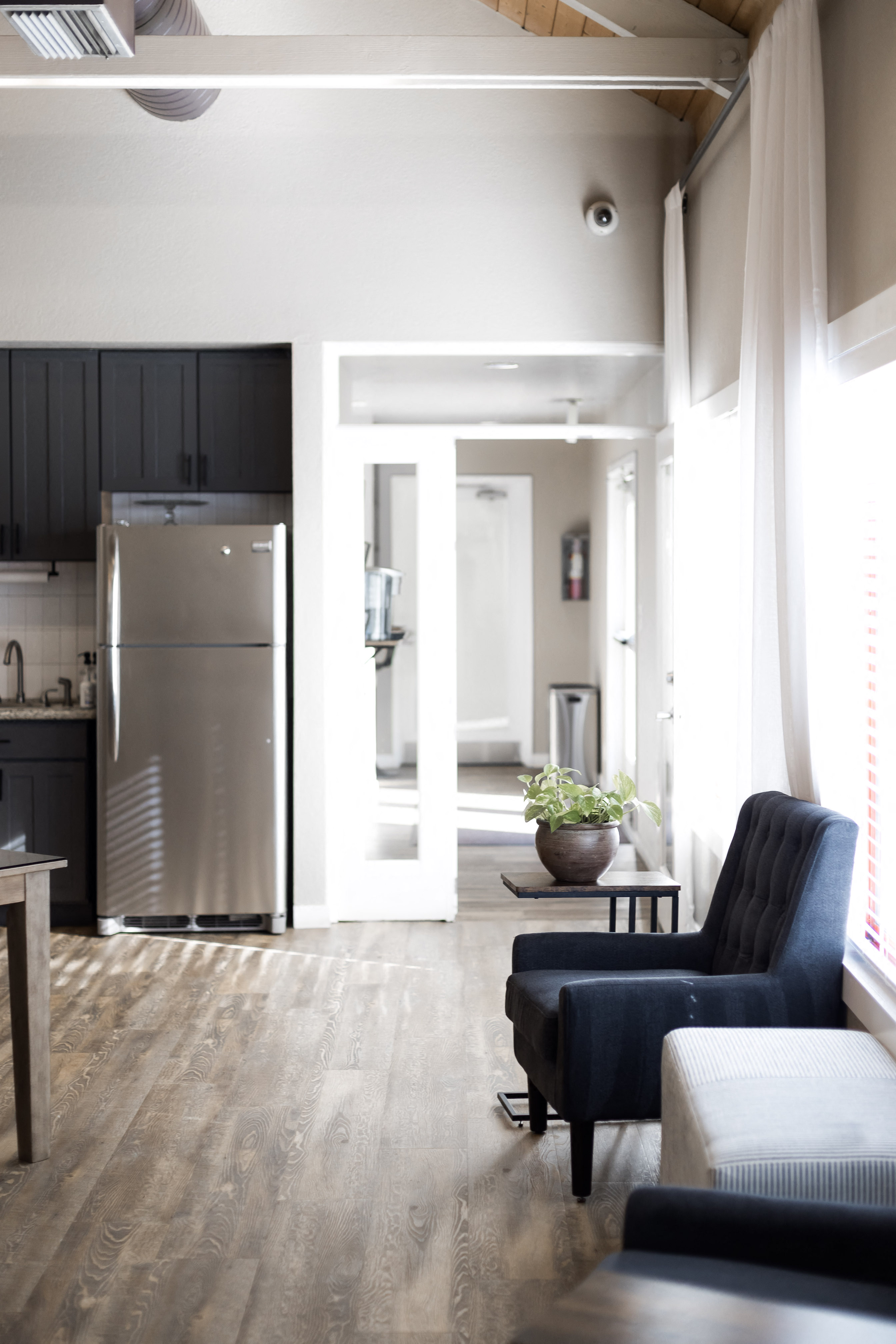a living room with a couch and a chair and a kitchen with a refrigerator