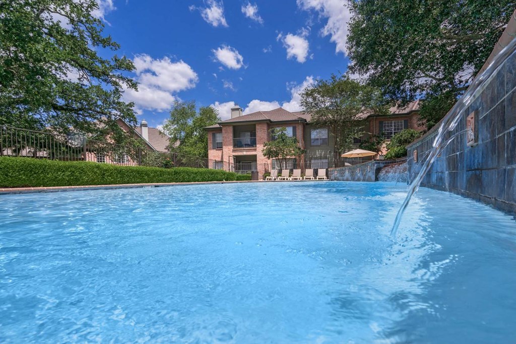 a large swimming pool with a fountain in front of a house