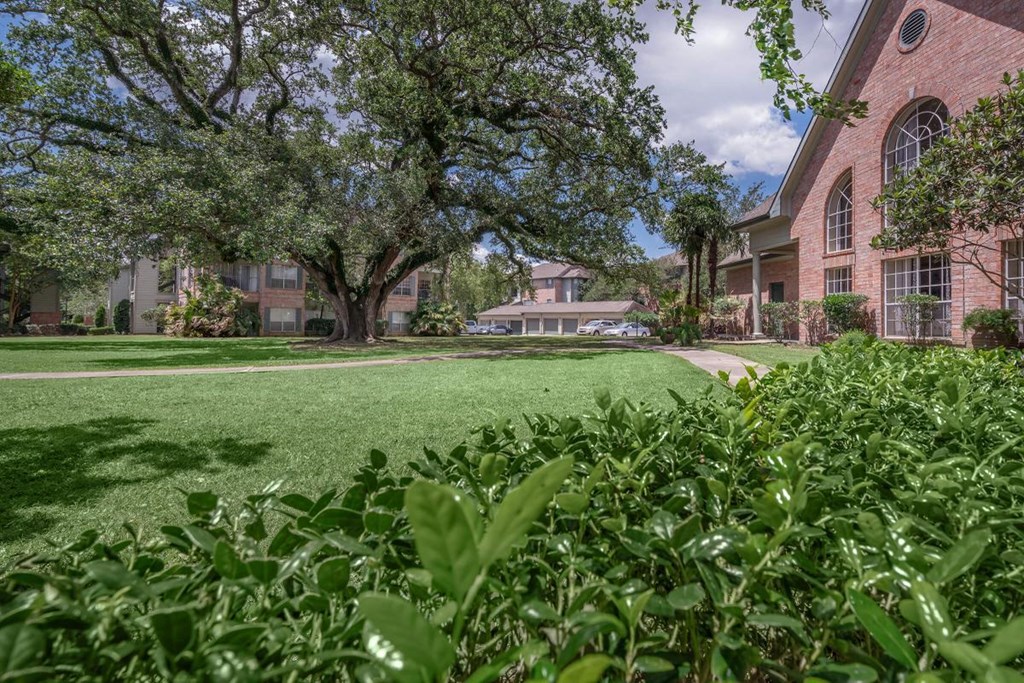 exterior view of a brick building with green grass and trees