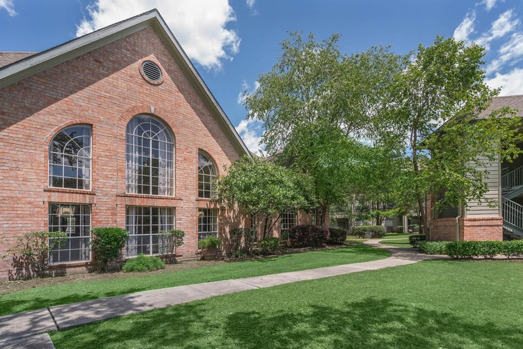 an exterior view of a brick building with grass and trees