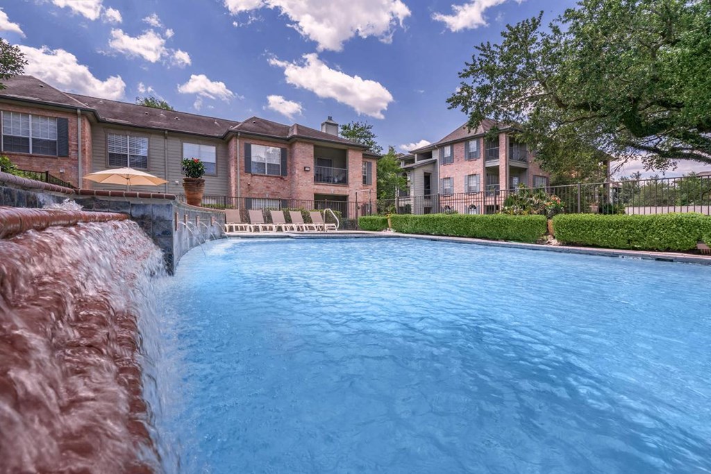 a swimming pool with a waterfall in front of an apartment building