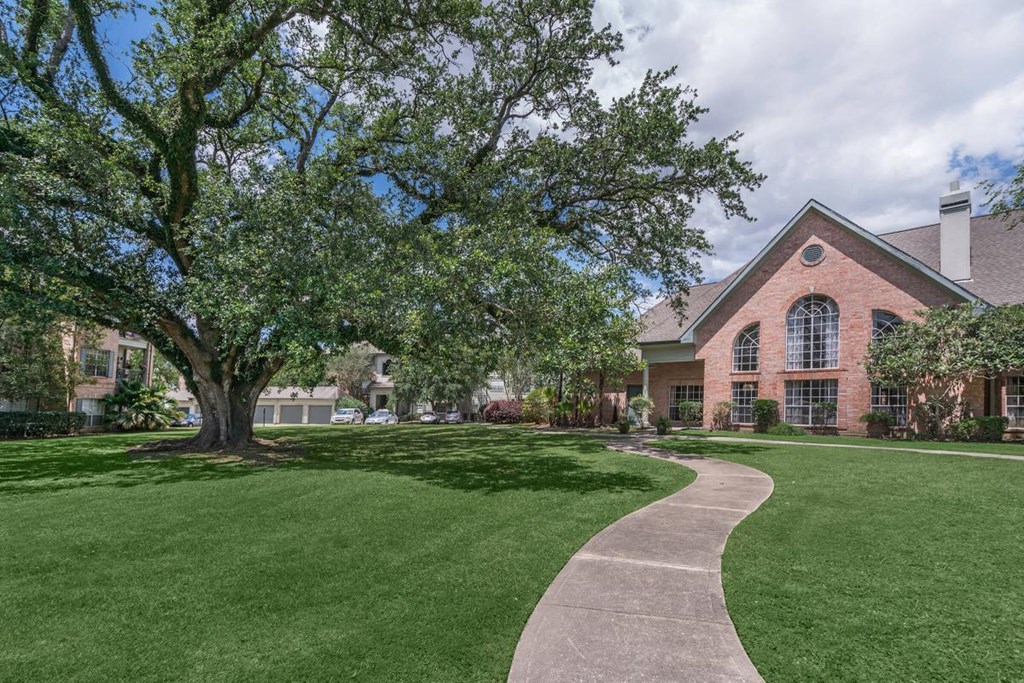 a walkway through the grass in front of a building