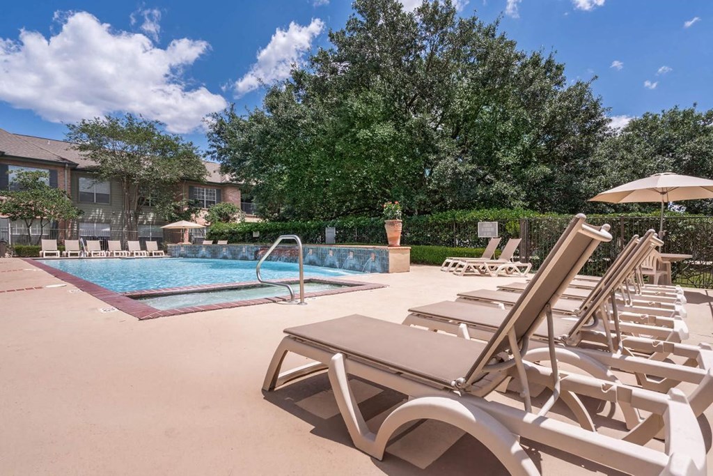 a pool with chairs and umbrellas at the resort on a sunny day