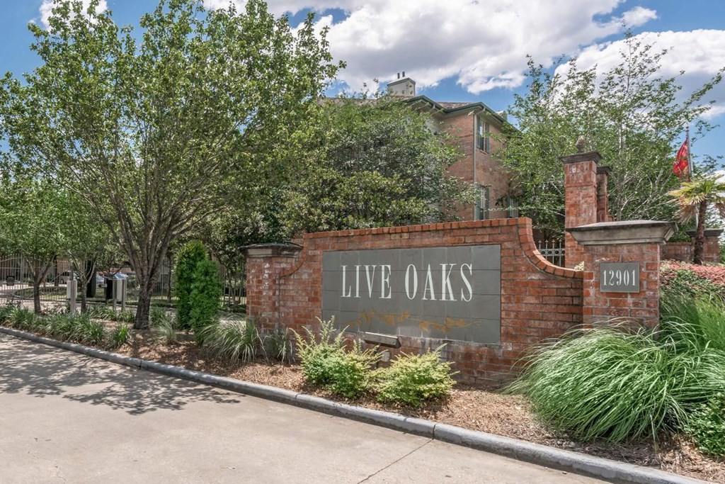 the sign for live oaks apartments in front of a brick wall