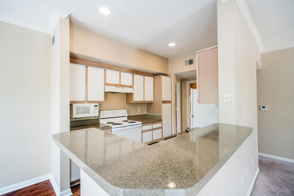 an empty kitchen with white cabinets and a counter top