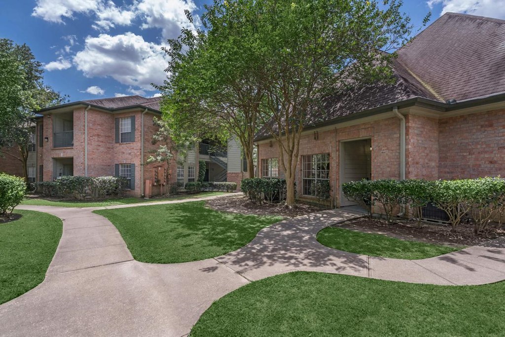 a sidewalk in front of a house with grass and trees