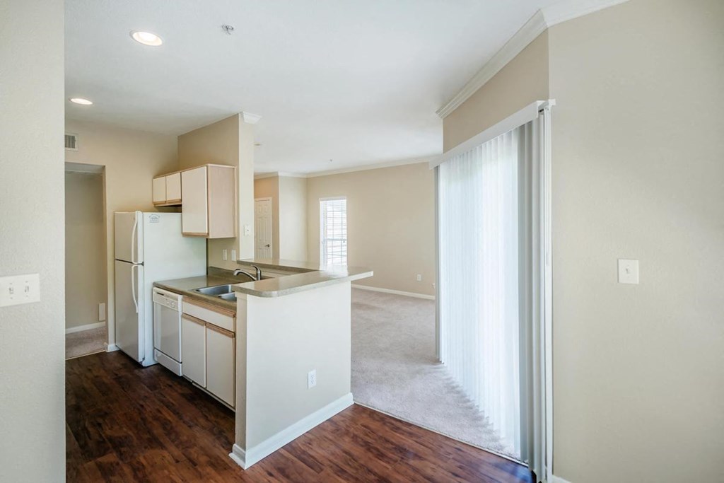 an empty kitchen with a sliding glass door to the living room