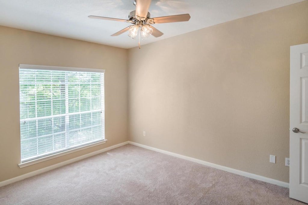 a bedroom with a large window and a ceiling fan