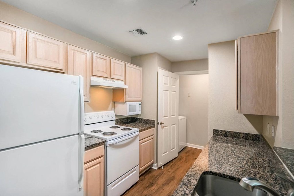 a kitchen with white appliances and granite counter tops