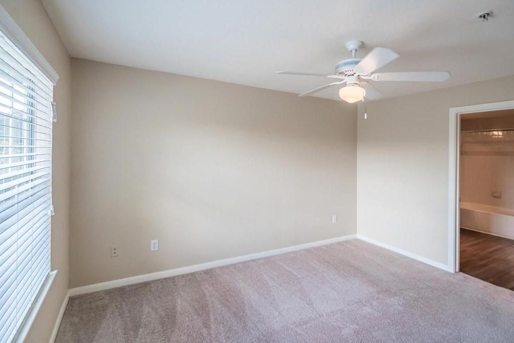 an empty living room with a ceiling fan and a door to a closet