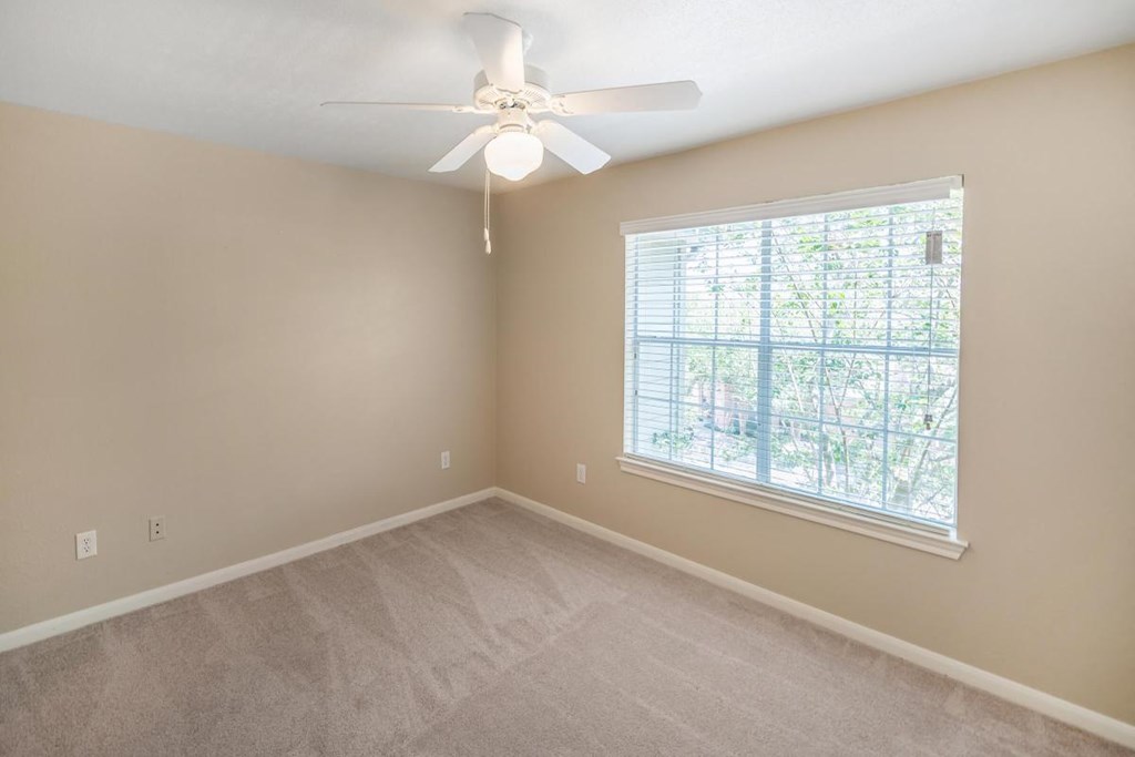a bedroom with a large window and a ceiling fan