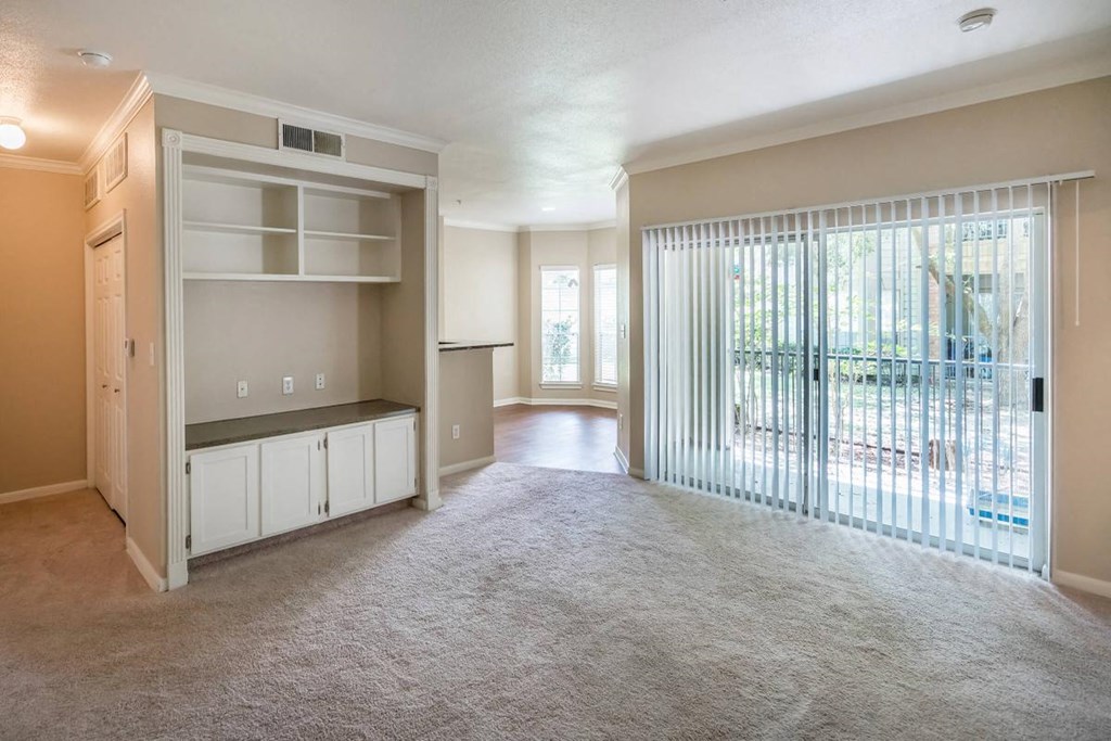 an empty living room with a sliding glass door to a balcony