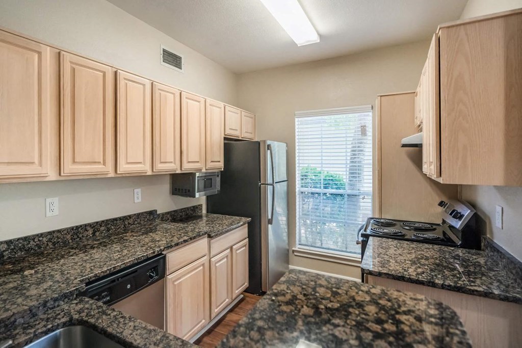 a kitchen with granite counter tops and a refrigerator