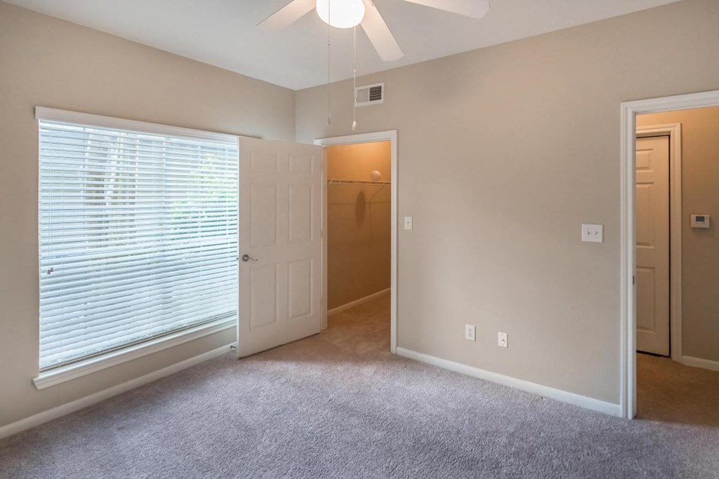 a bedroom with a large window and a door to a closet