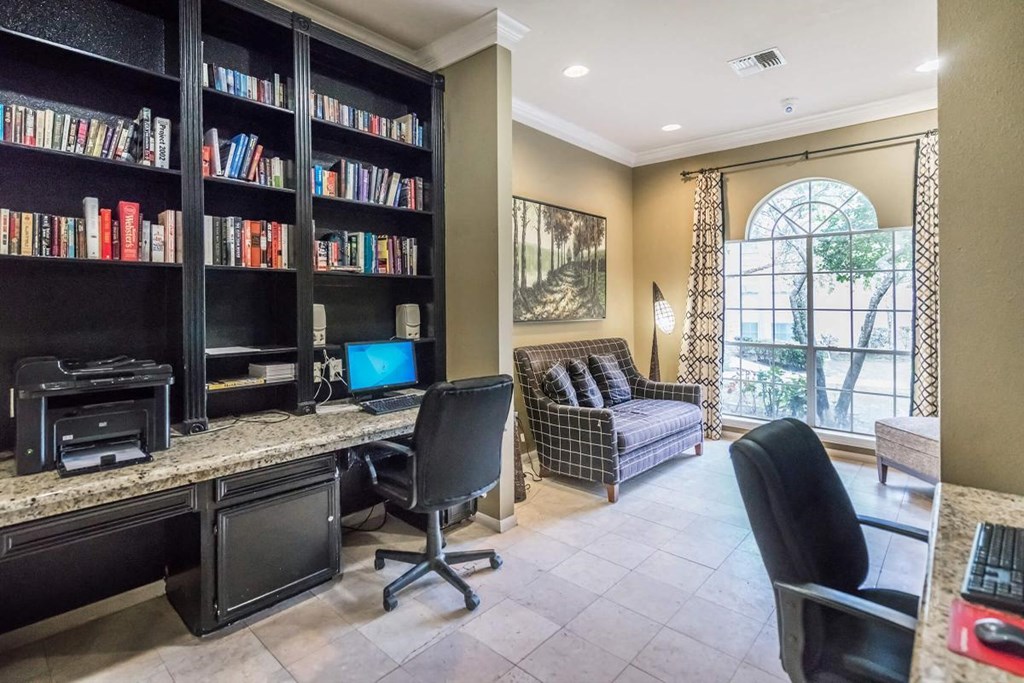 a library with a desk and chairs and a window