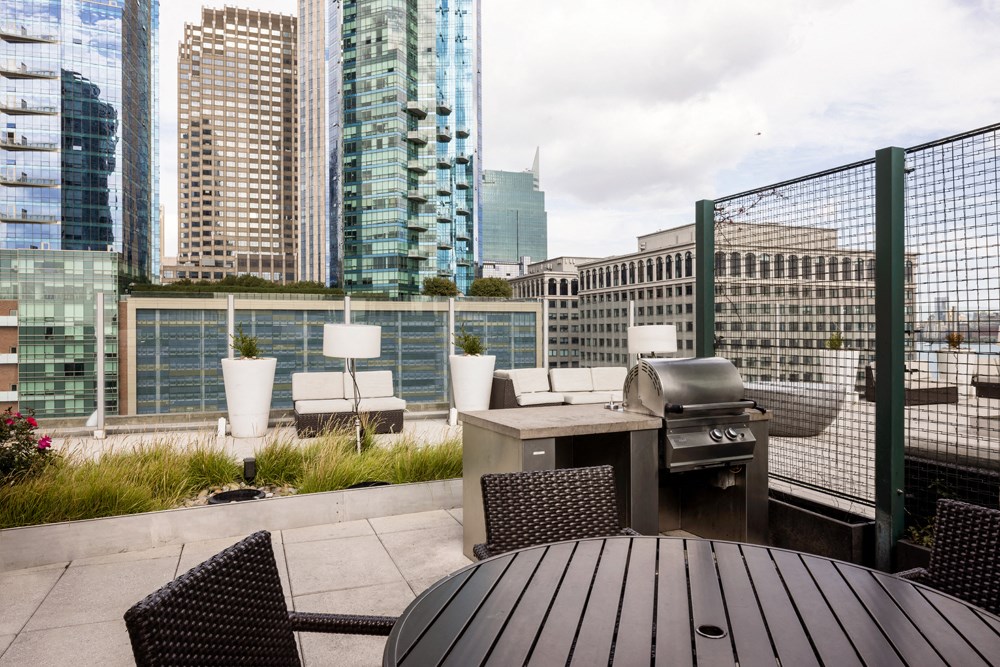a patio with a grill and a table on a rooftop
