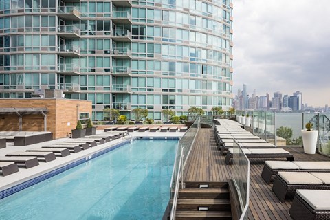 a swimming pool on the roof of an apartment building with a city in the background