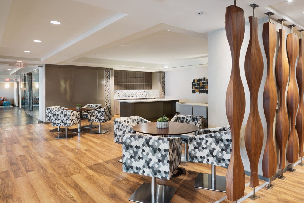 a room with tables and chairs and a kitchen in the background