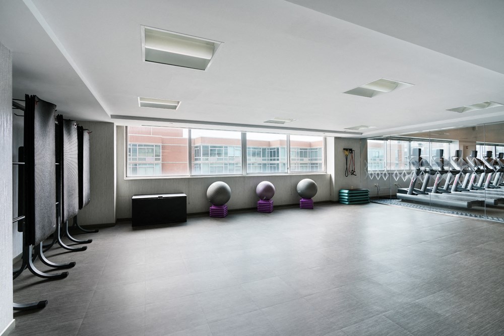 a large fitness room with chairs and a row of windows