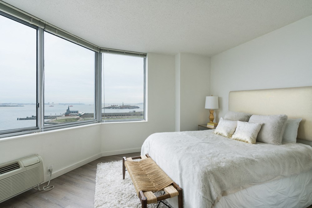 a bedroom with a bed and a large window with a view of the ocean