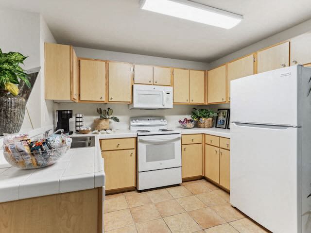 A kitchen with wooden cabinets and white appliances.
