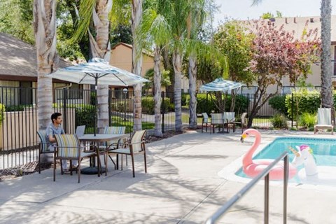 a man sitting at a table next to a swimming pool