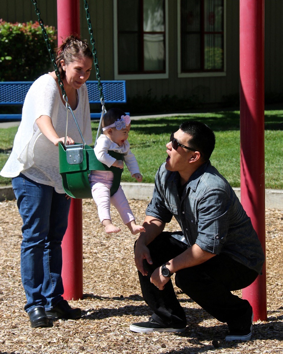 a man and a woman playing with a child on a swing