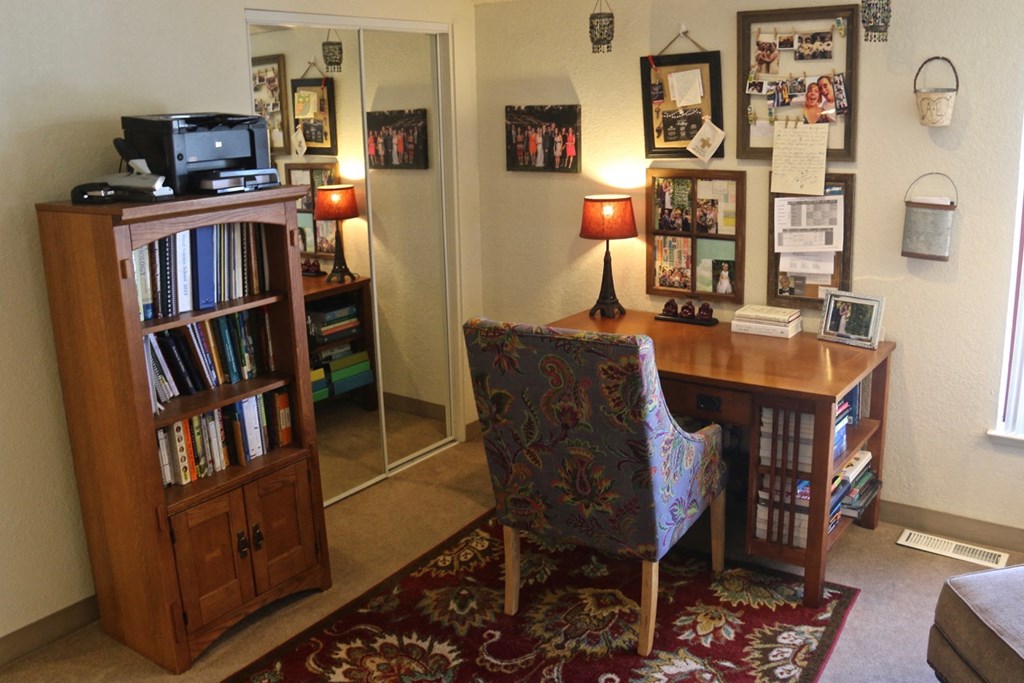 a home office with a desk and a chair and a bookcase with a mirror