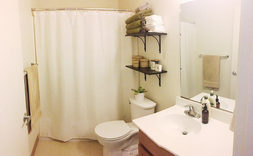 a bathroom with a white shower curtain and a toilet and sink