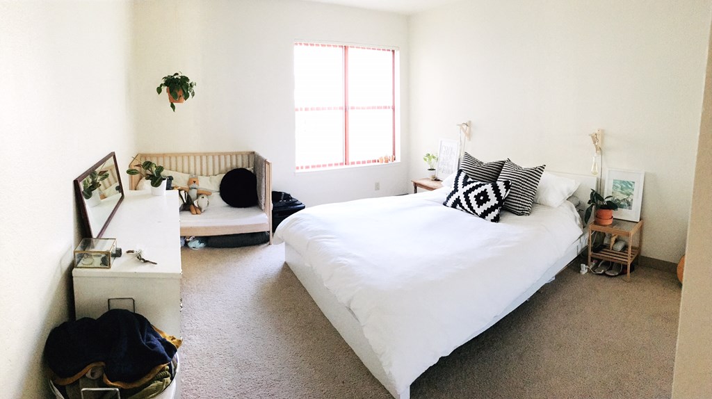 a bedroom with a white bed and a window     and a chair