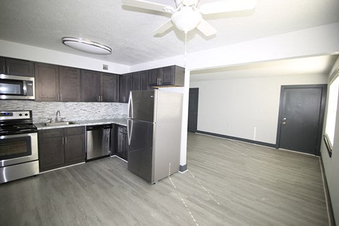 an empty kitchen with stainless steel appliances and a ceiling fan