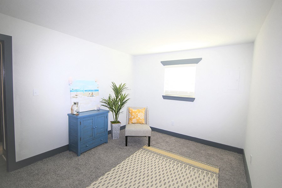 a living room with a chair and a plant and a window