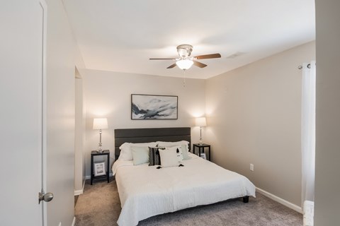 A bedroom with a bed, two lamps, and a painting on the wall.