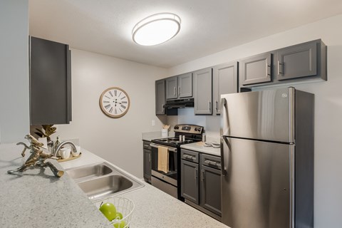 A kitchen with a stainless steel refrigerator, microwave, oven, and sink.