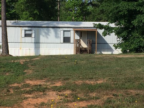 a house with a porch and a fence in a field