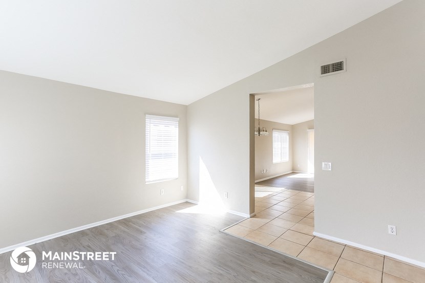 the living room and hallway of an empty house with white walls and wood floors