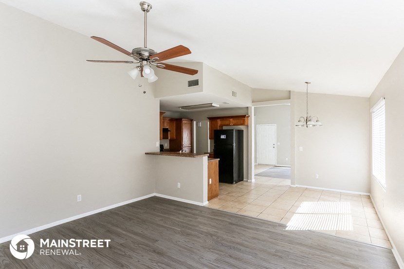 a living room with a ceiling fan and a kitchen