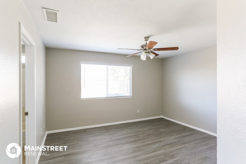 an empty room with a ceiling fan and a window