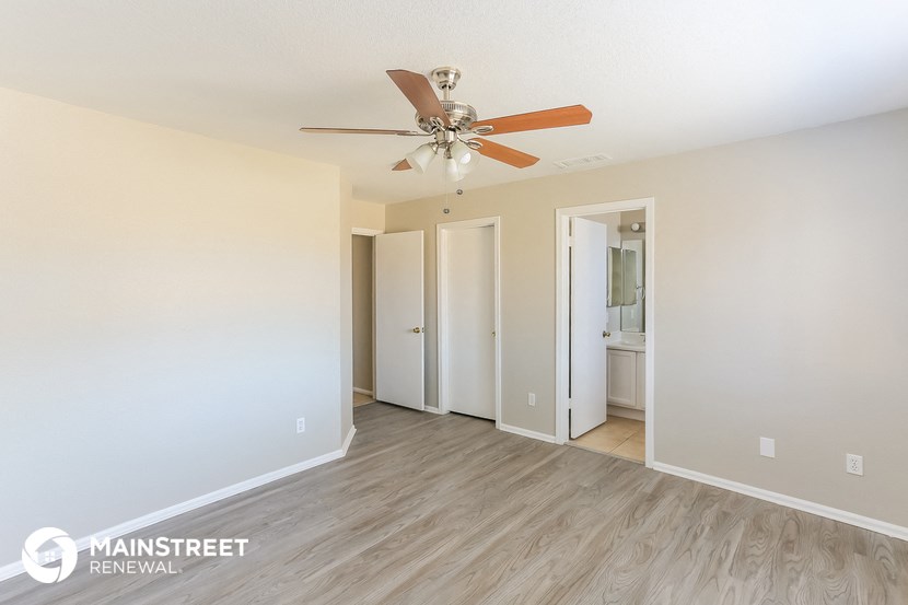 the spacious living room with ceiling fan and wood flooring