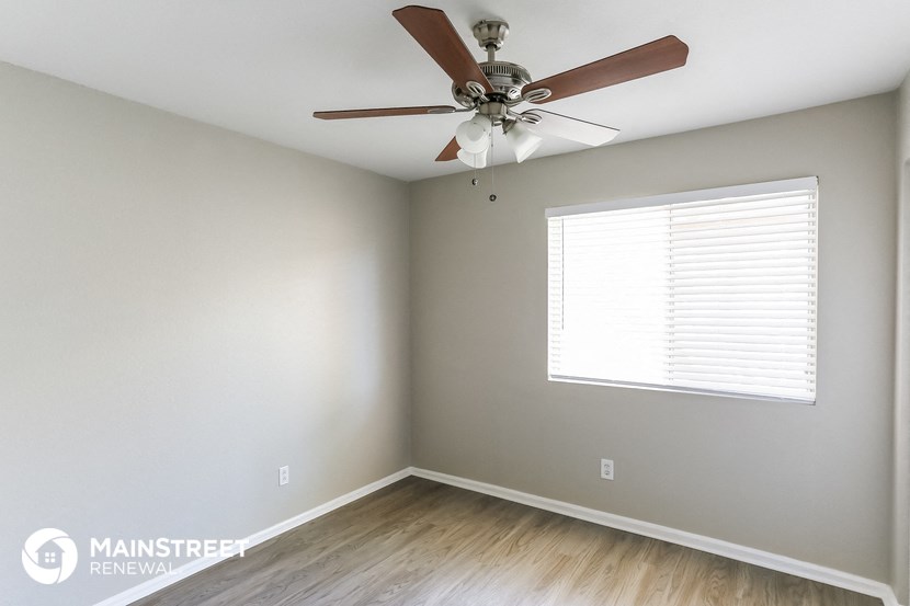an empty room with a ceiling fan and a window