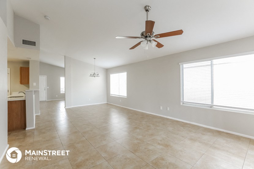 an empty living room with a ceiling fan and a large window