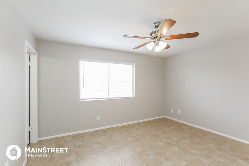 the spacious living room with ceiling fan and tile flooring