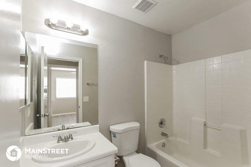 a white bathroom with a tub and a sink and a mirror