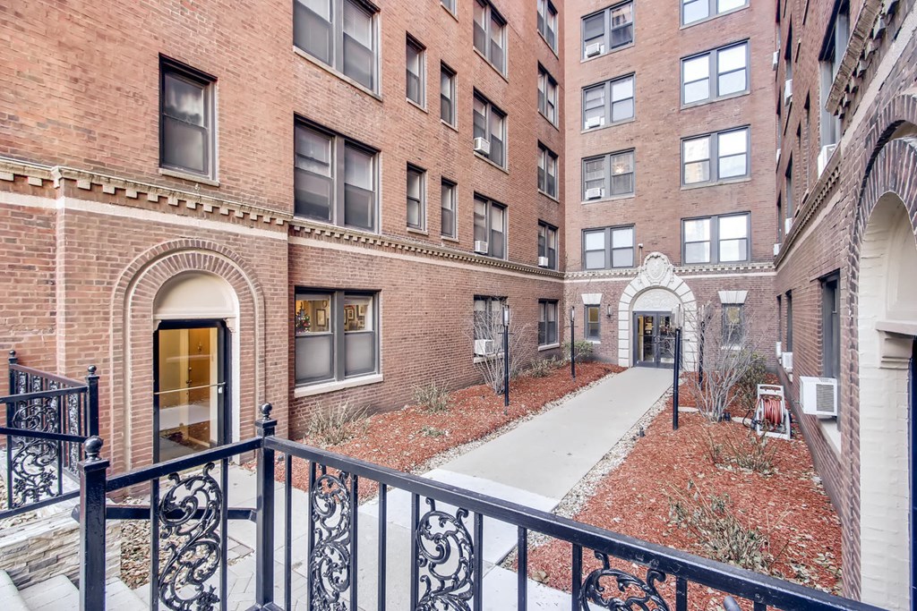 the entrance to a brick apartment building with a sidewalk