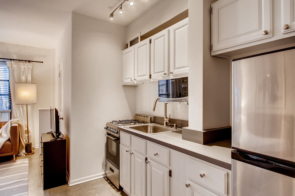 a kitchen with white cabinets and a stainless steel refrigerator