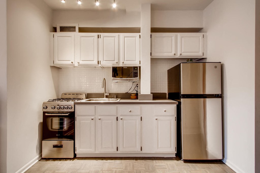 a kitchen with white cabinets and a stainless steel refrigerator