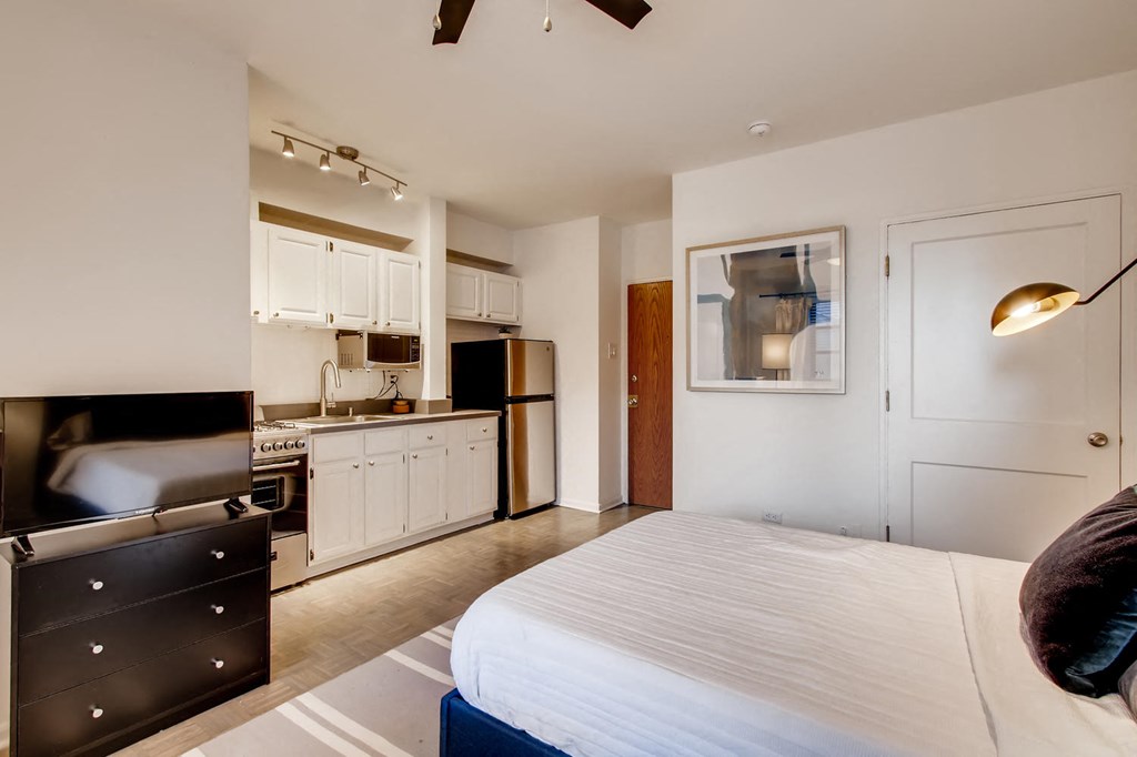 a bedroom with a bed and a kitchen in the background