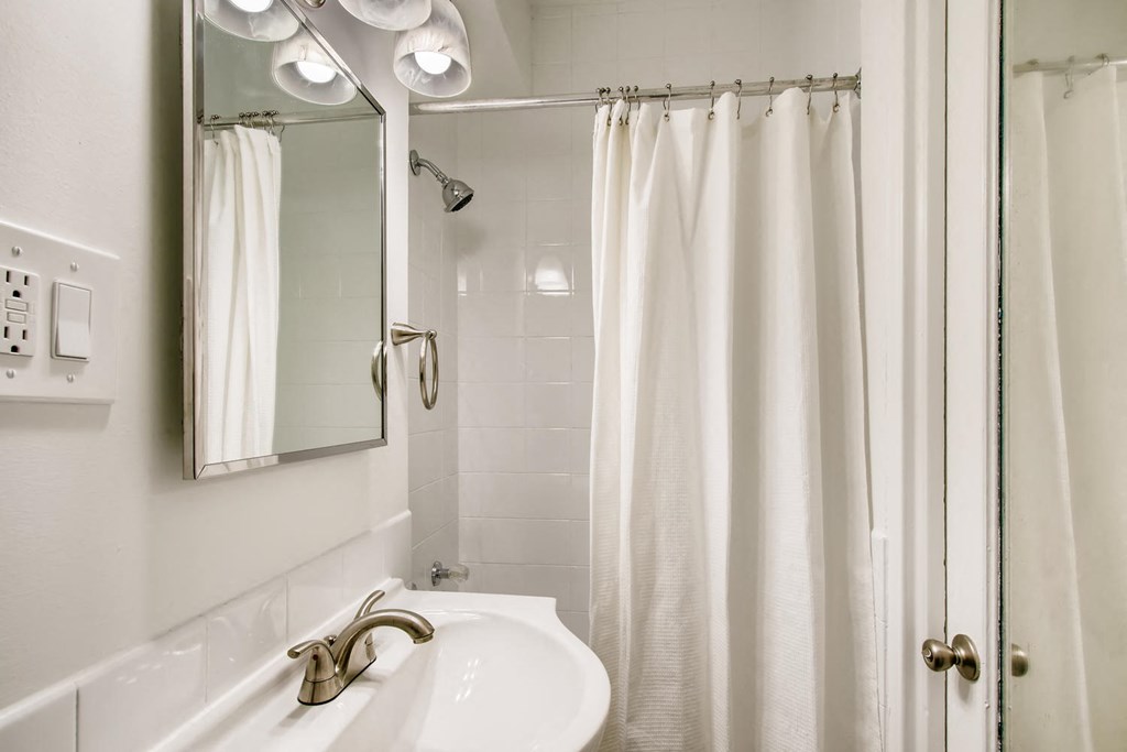 a white bathroom with a shower and a sink